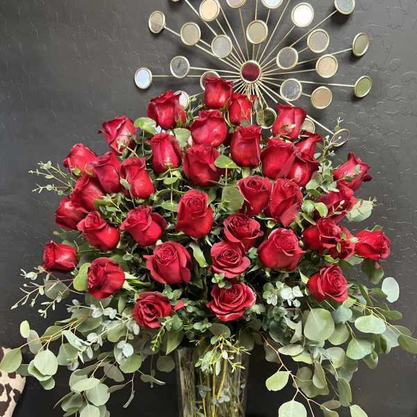 Tall vase arrangement of red roses with eucalyptus