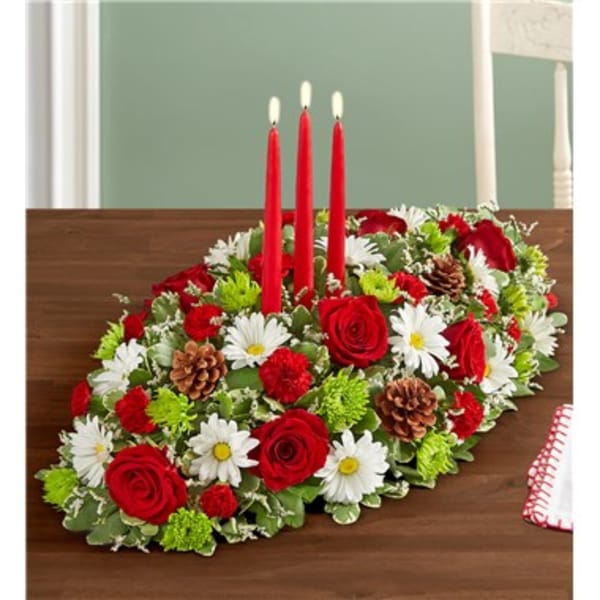 Oval table centerpiece with red roses, white daisies, and three red candles