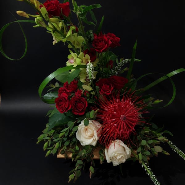 Tall floral arrangement with red and white roses and green orchids