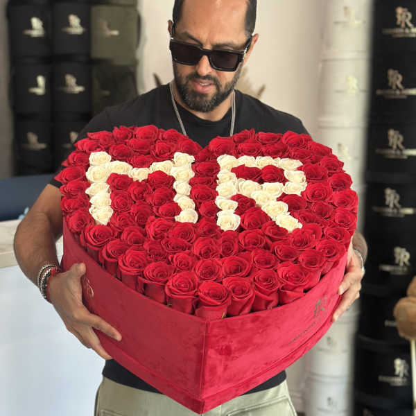 Heart-shaped box of red and white roses held by a man