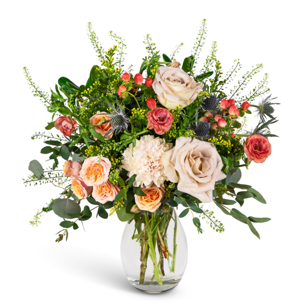 Bouquet of cream and peach roses with white blooms in a clear glass vase