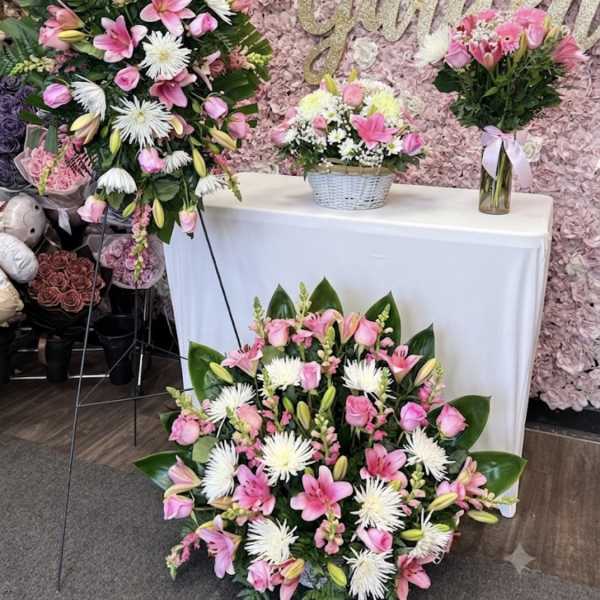Pink and white floral arrangements with lilies and roses at a decorated display