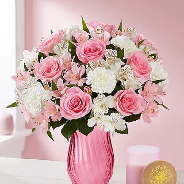 Pink roses and white flowers arranged in a pink glass vase