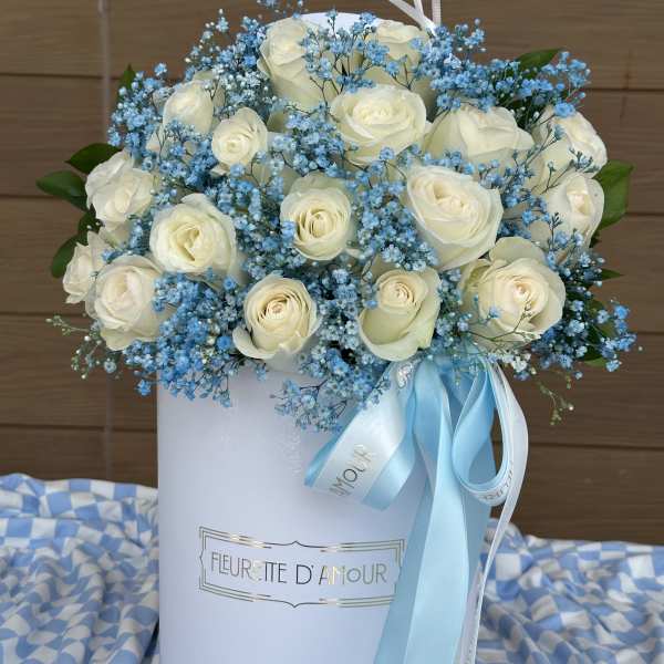 White roses and blue baby's breath in a white hatbox with ribbon