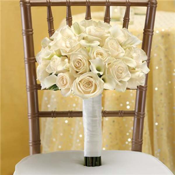 White rose and calla lily bouquet tied with white ribbon on a chair