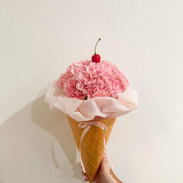 Pink carnation bouquet in a waffle cone with a cherry topper