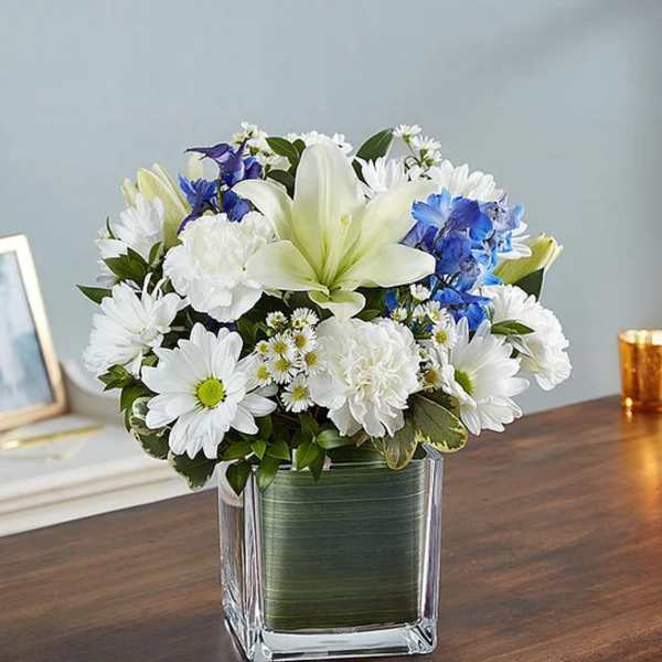 White and blue mixed bouquet in a square glass vase