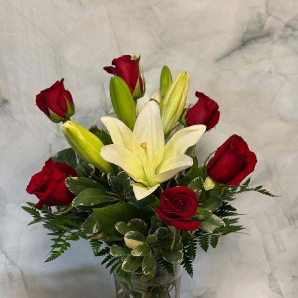 Red roses and white lilies arranged in a clear glass vase
