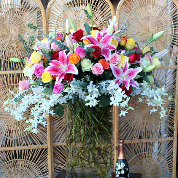Mixed bouquet of roses and lilies in a tall glass vase