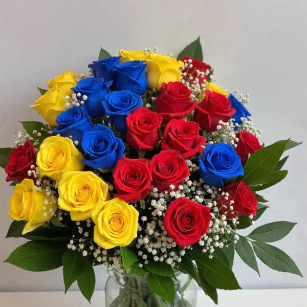 Bouquet of red, yellow, and blue roses in a clear glass vase