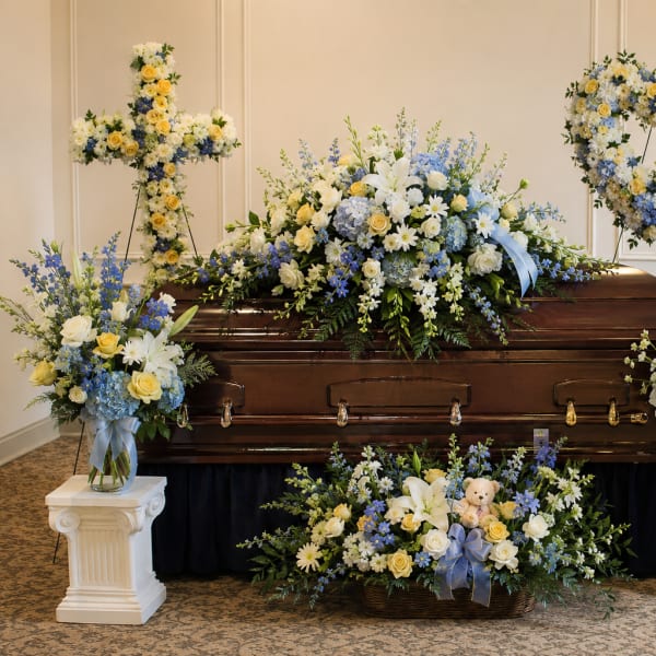 Casket surrounded by blue, white, and yellow funeral flower arrangements