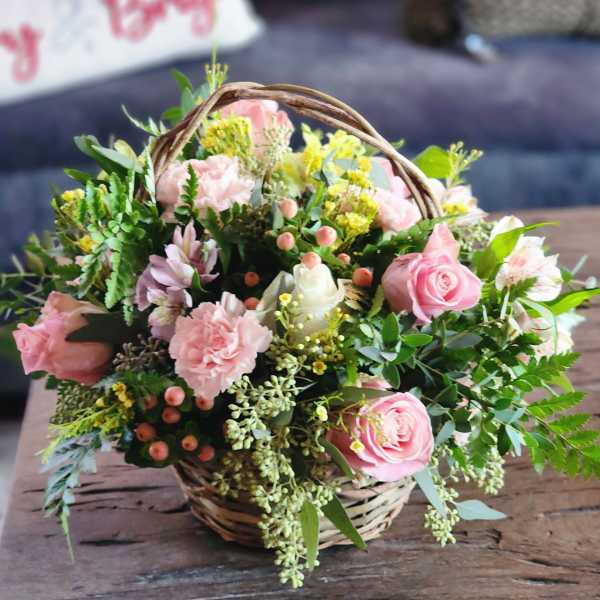 Pink roses and carnations in a wicker basket