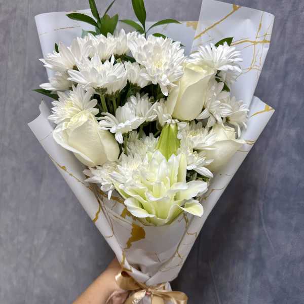 White bouquet with daisies, roses, and a lily wrapped in patterned paper