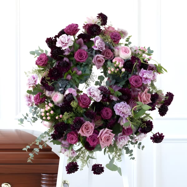 Large purple and pink floral wreath on a white stand