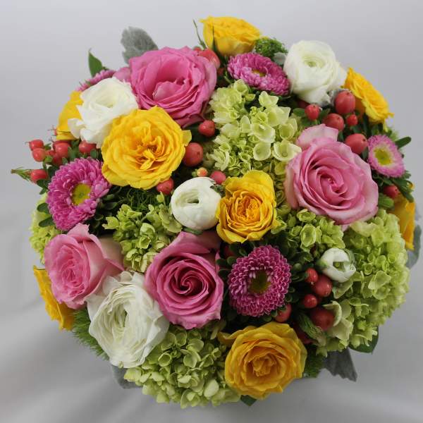 Round bouquet of pink, yellow, and white flowers with green hydrangeas