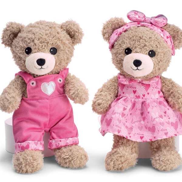 Two teddy bears in pink outfits, one in overalls and one in a dress