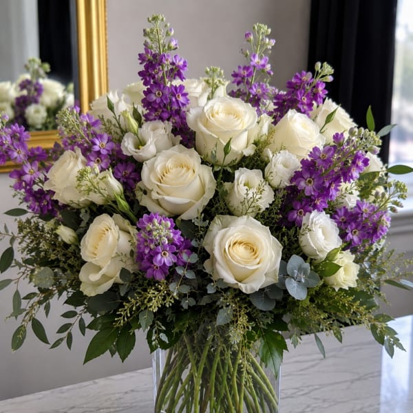 White roses and purple flowers in a clear glass vase