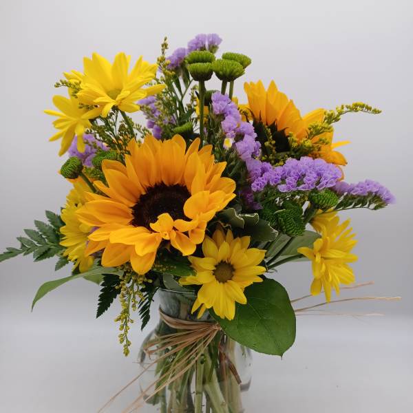 Bouquet of yellow sunflowers and purple flowers in a glass vase