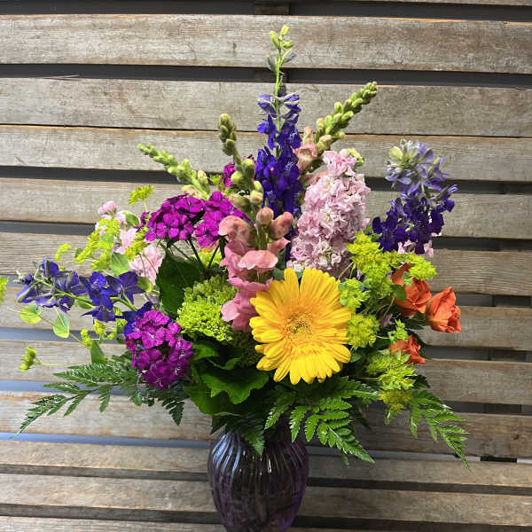 Colorful mixed flower arrangement in a dark glass vase