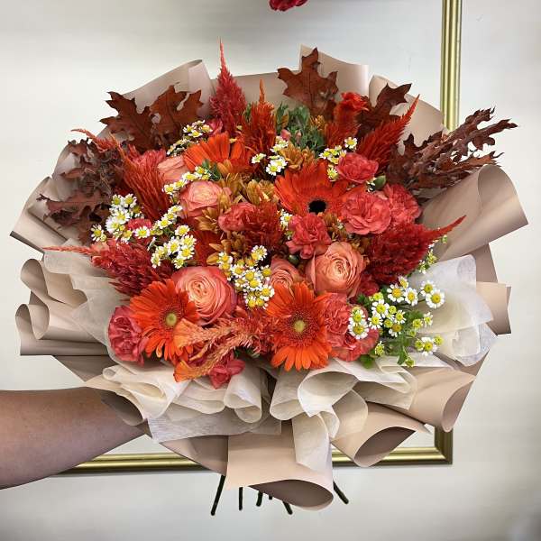 Bouquet of orange and pink flowers wrapped in beige paper