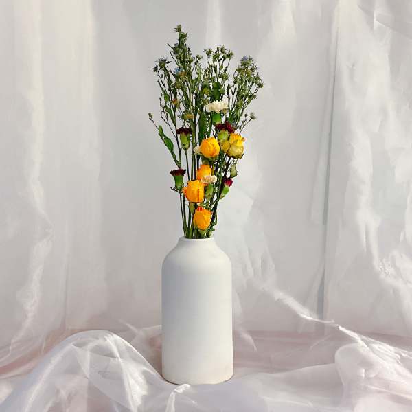 Tall bouquet of yellow and white roses in a white vase