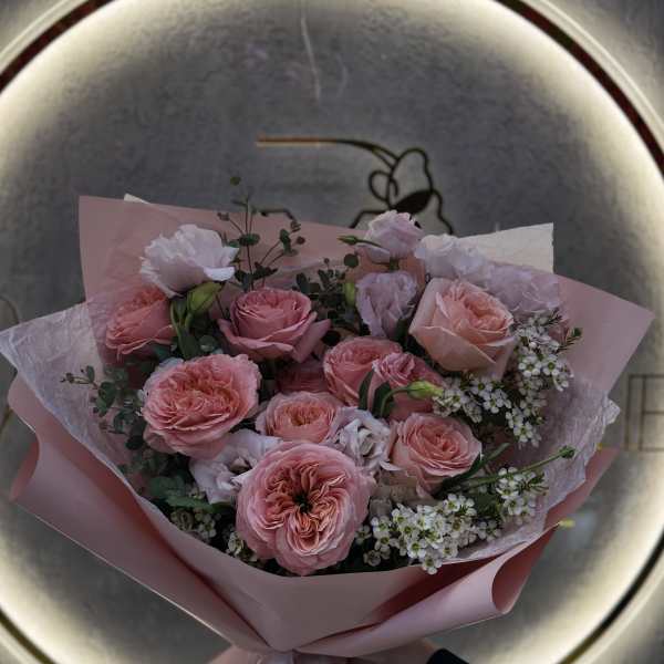 Pink rose bouquet wrapped in pastel paper with a white ribbon