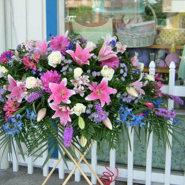 Large standing spray of pink lilies, white roses, and purple flowers