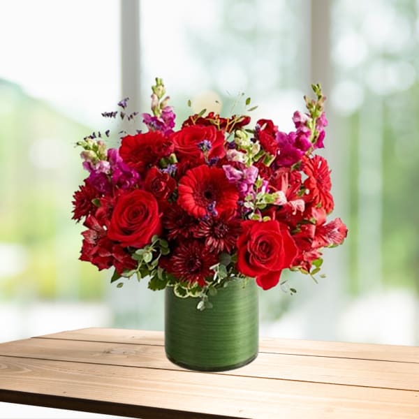 Red mixed flower arrangement in a green vase