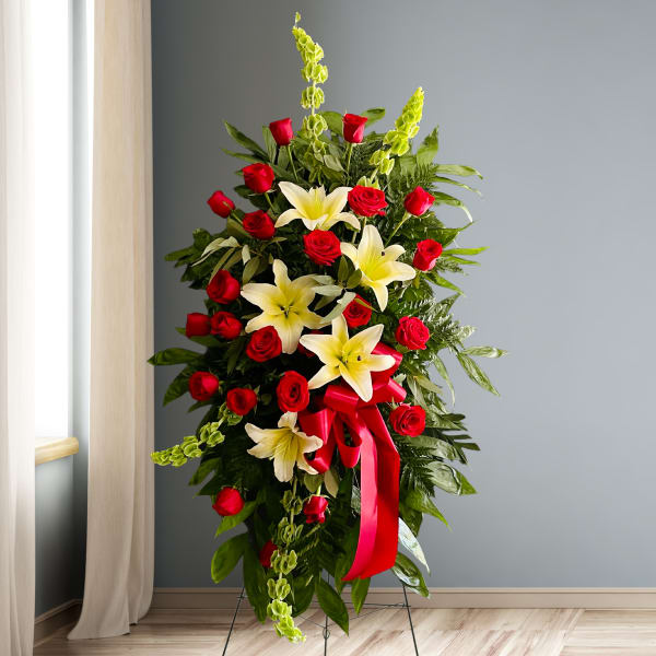 Standing floral spray with red roses, white lilies, and a red ribbon