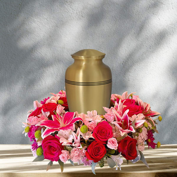 Pink and red floral arrangement around a gold urn