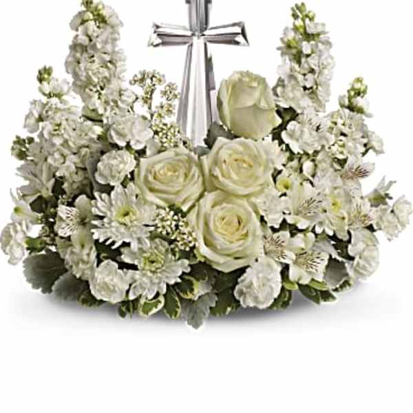 White floral arrangement with roses and stock around a silver cross