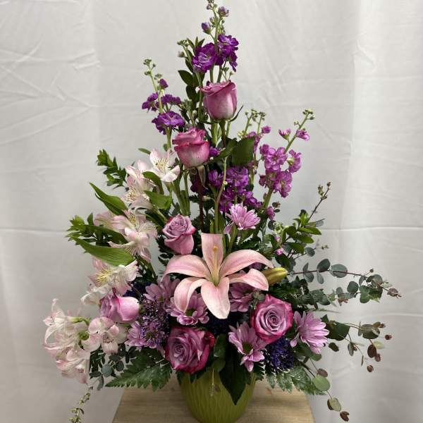 Tall pink and purple floral arrangement in a green vase