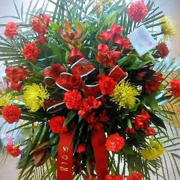 Tall red and yellow floral standing arrangement with ribbon streamers