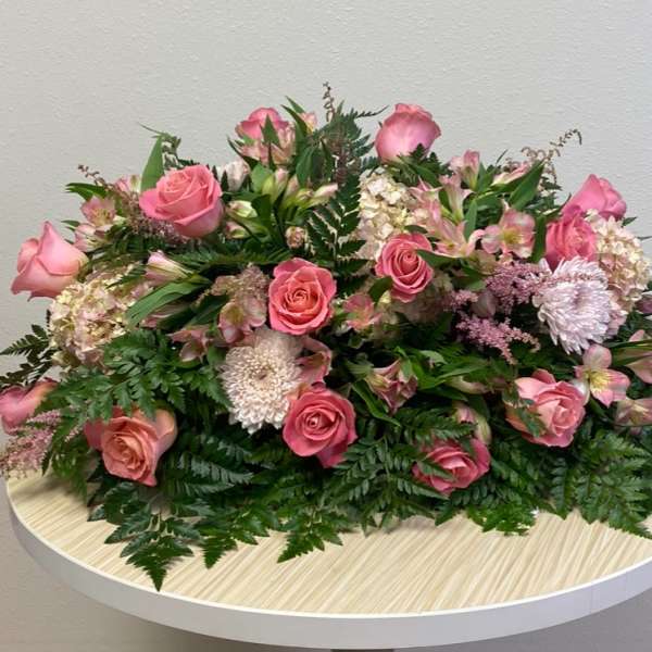 Pink roses and mixed blooms arranged low on a round table