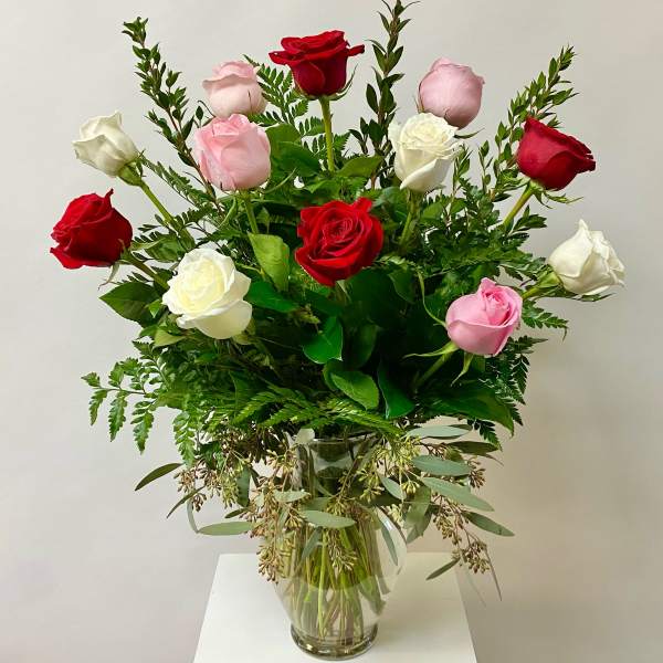 Bouquet of red, pink, and white roses in a clear glass vase
