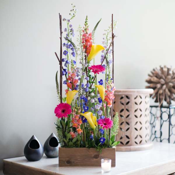 Tall mixed flower arrangement in a wooden box with yellow calla lilies and pink gerberas