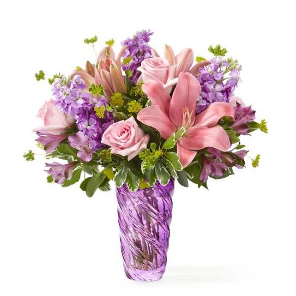 Pink lilies and roses arranged in a purple glass vase