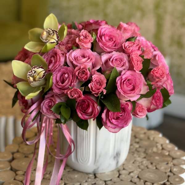 Pink rose bouquet with two pale green orchids in a white vase