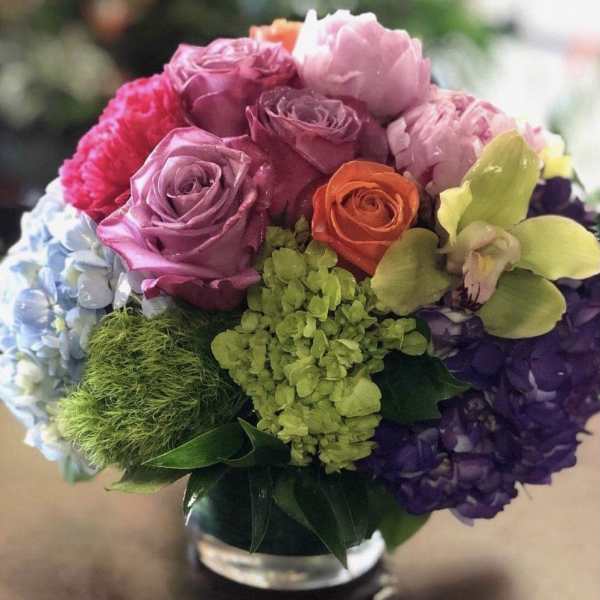 Colorful bouquet of roses, hydrangeas, and orchids in a glass vase