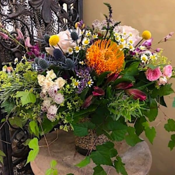 Mixed bouquet with orange, pink, purple, and white flowers in a vase