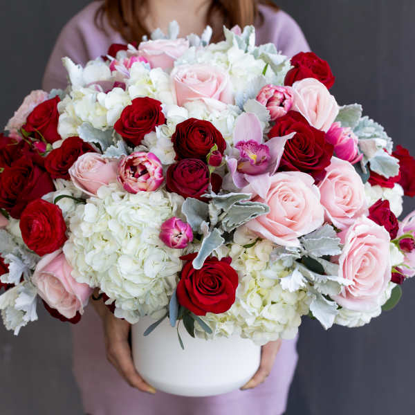 Large bouquet of red and pink roses with white hydrangeas in a white vase