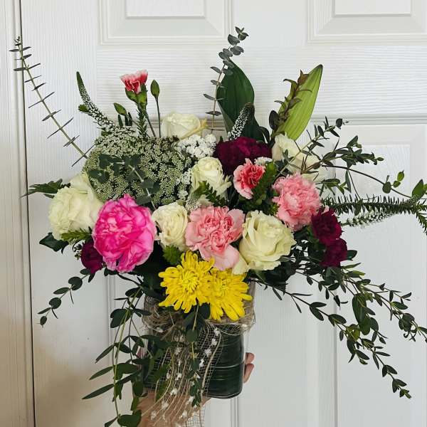 Mixed bouquet of roses, carnations, and chrysanthemums in a dark vase