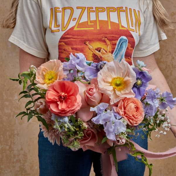Handheld bouquet of pastel flowers with a pink ribbon