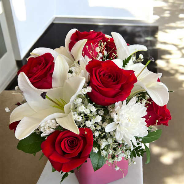 Red roses and white lilies in a pink vase
