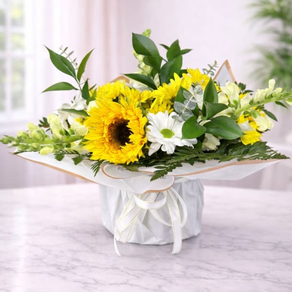 Yellow sunflowers and white daisies in a wrapped bouquet box