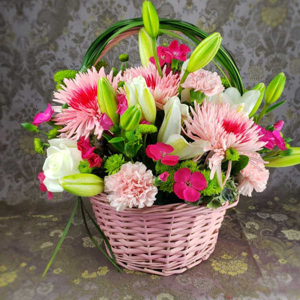 Pink basket of mixed flowers with lilies, roses, and carnations
