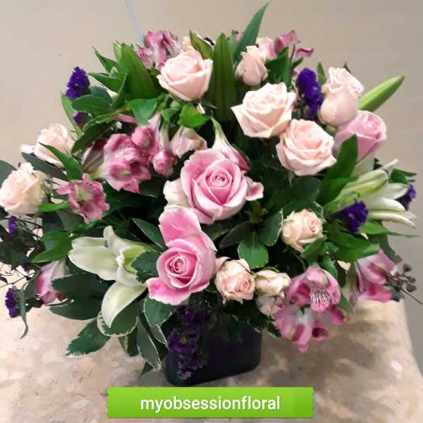 Pink roses and lilies arranged in a dark vase