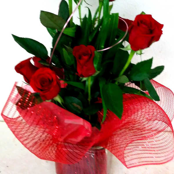 Bouquet of red roses in a clear glass vase with red mesh wrap