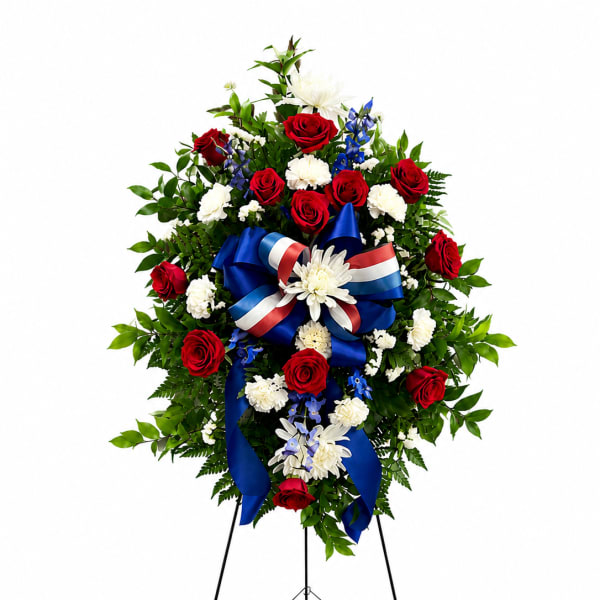 Standing floral wreath with red and white flowers and a blue ribbon on an easel