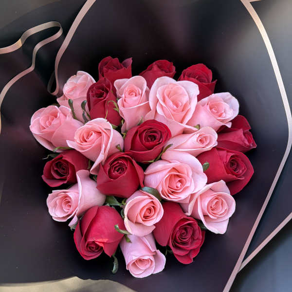 Bouquet of pink and red roses wrapped in black paper